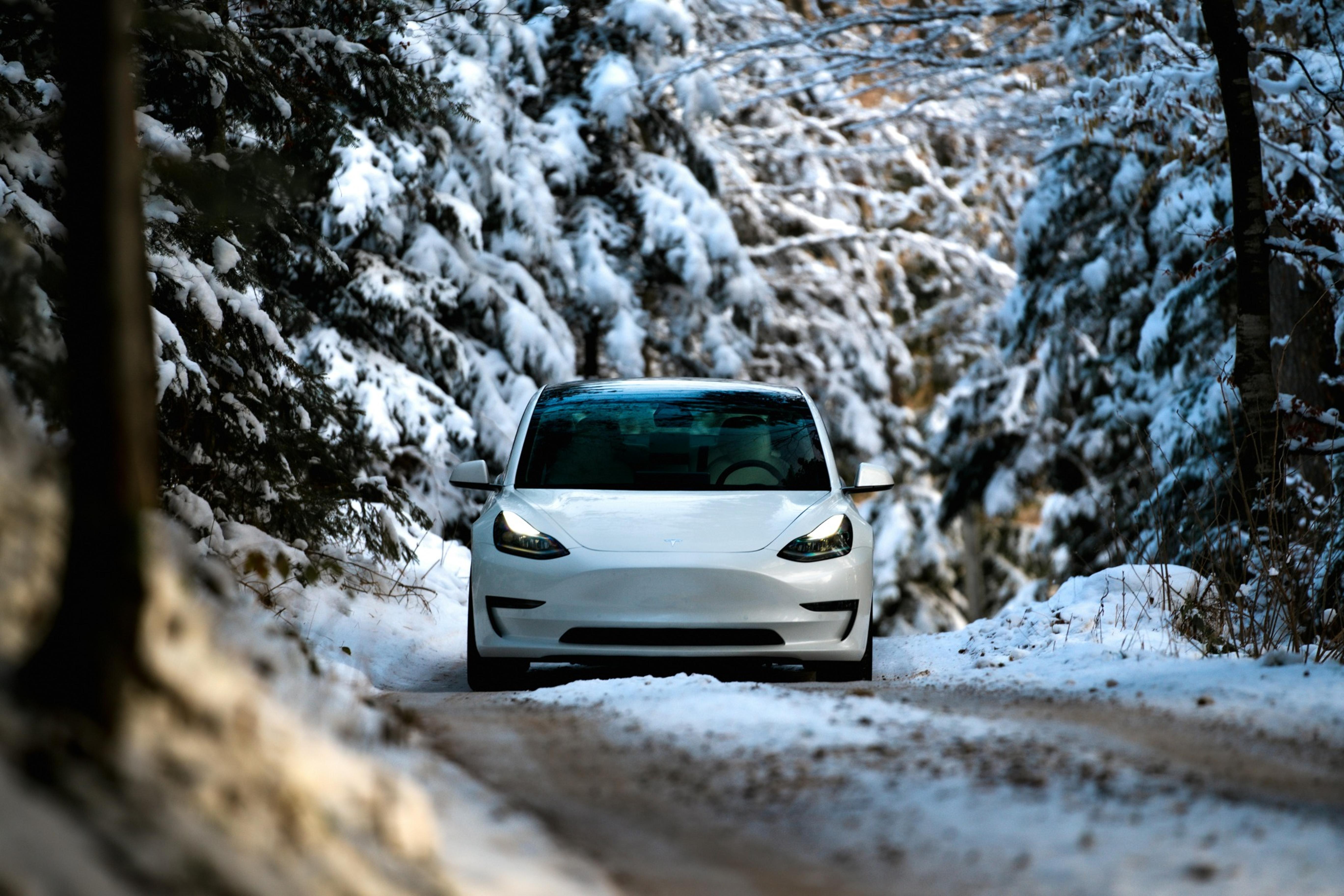 White Tesla driving through the winter with preconditioned battery