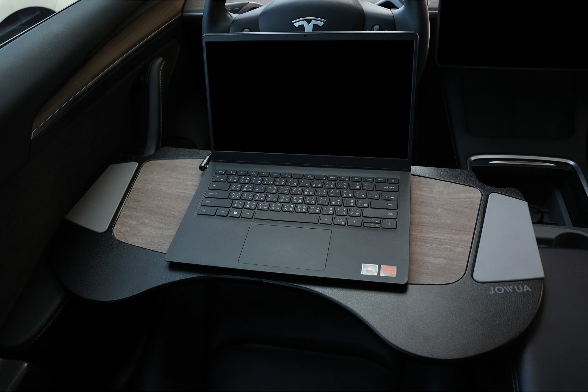 Inside a Tesla, a laptop rests on a sleek wooden car tray positioned over the steering wheel. Crafted from high-quality material, this tray is designed specifically for workspace use, seamlessly blending with the modern car interior while supporting efficient productivity on the go with the integration of JOWUA's 100W USB-C to Magnetic DC Charging Cable for fast charging.