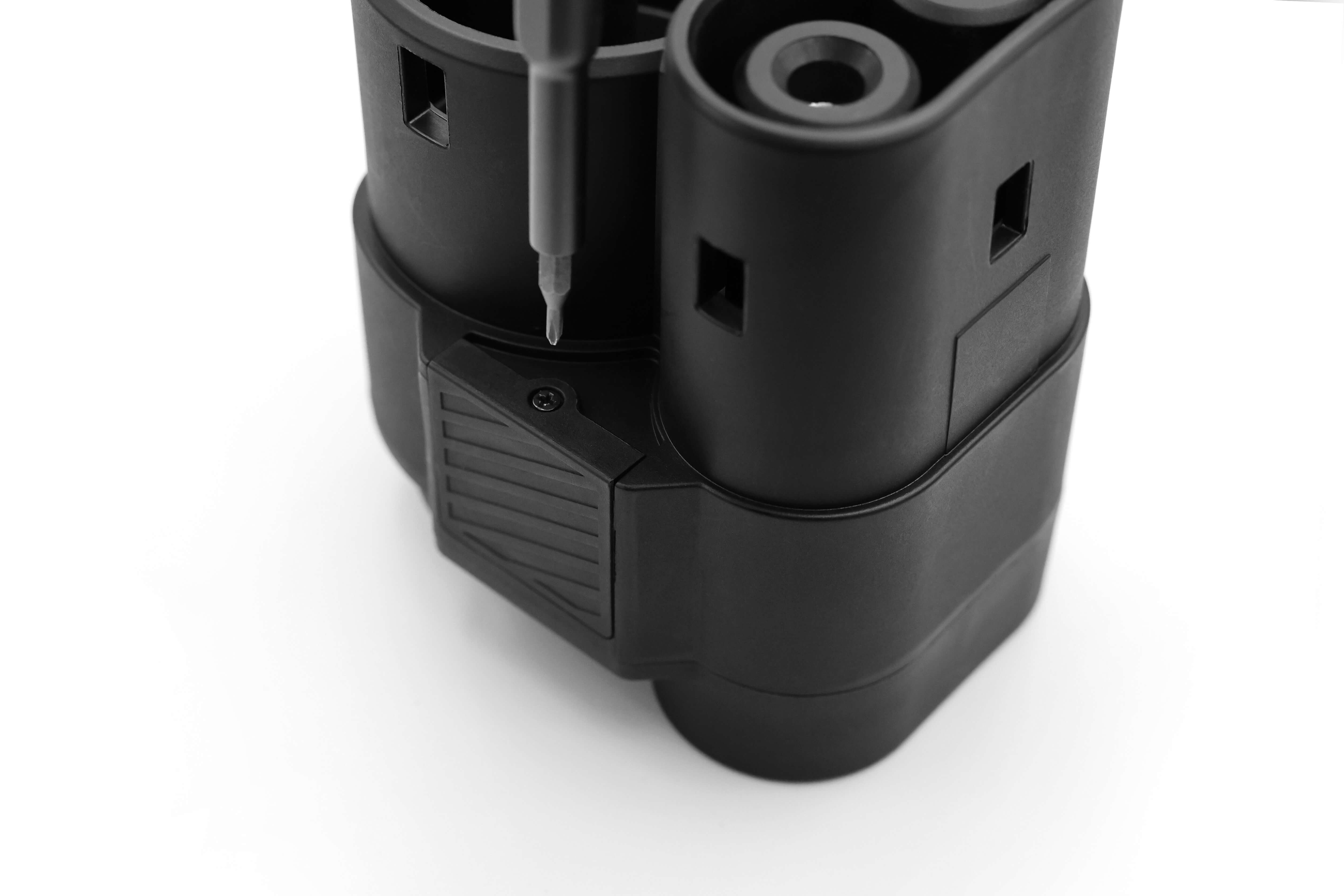 Close-up of a black, cylindrical electronic device resembling the advanced JOWUA CCS1 to CCS2 Adapter on a white background. The device showcases several round compartments with a pen-like tool inserted into one of them, mirroring the precision of supercharging stations.