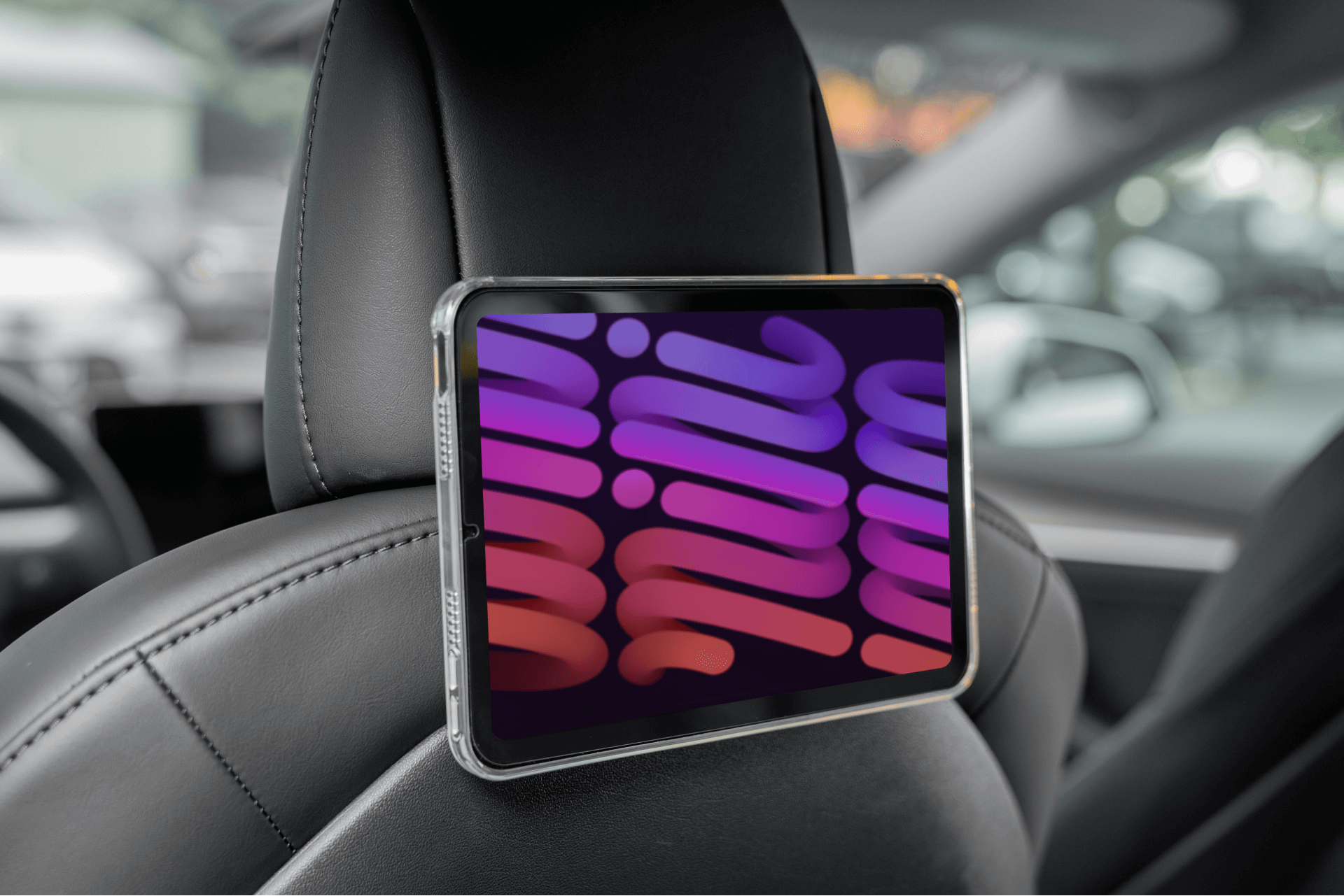 The JOWUA Taiwan Hook Bundle (Model Y) is effortlessly installed on a car headrest, featuring a vibrant screen displaying abstract shapes in purple and pink tones. The car's contemporary interior highlights sleek comfort with its black leather seats.