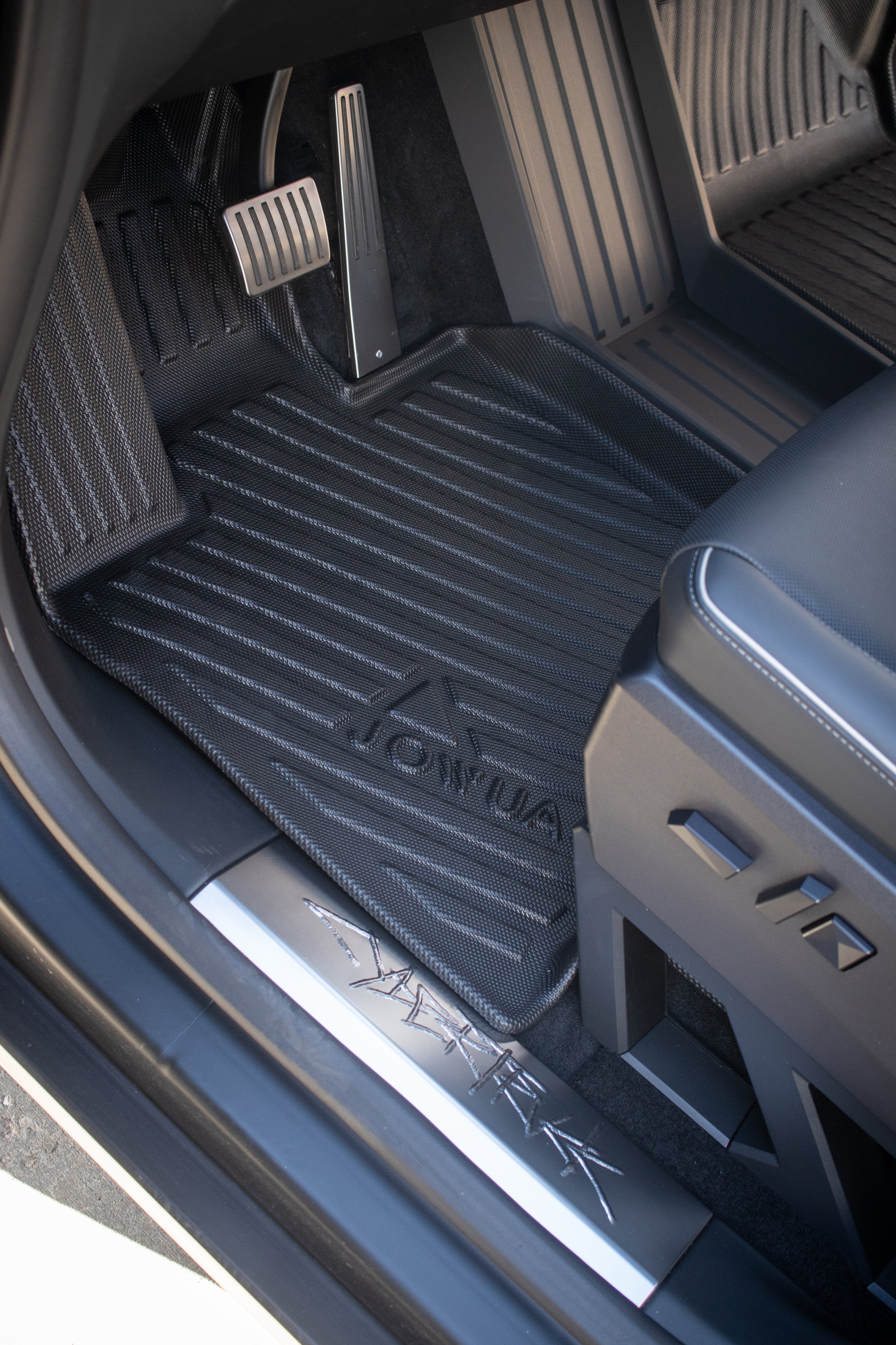 The interior close-up reveals JOWUA All Weather Floor Liners for Tesla Cybertruck, showcasing pedals and a textured black liner with the brand name. The design combines metallic and fabric elements for a sleek, modern aesthetic.