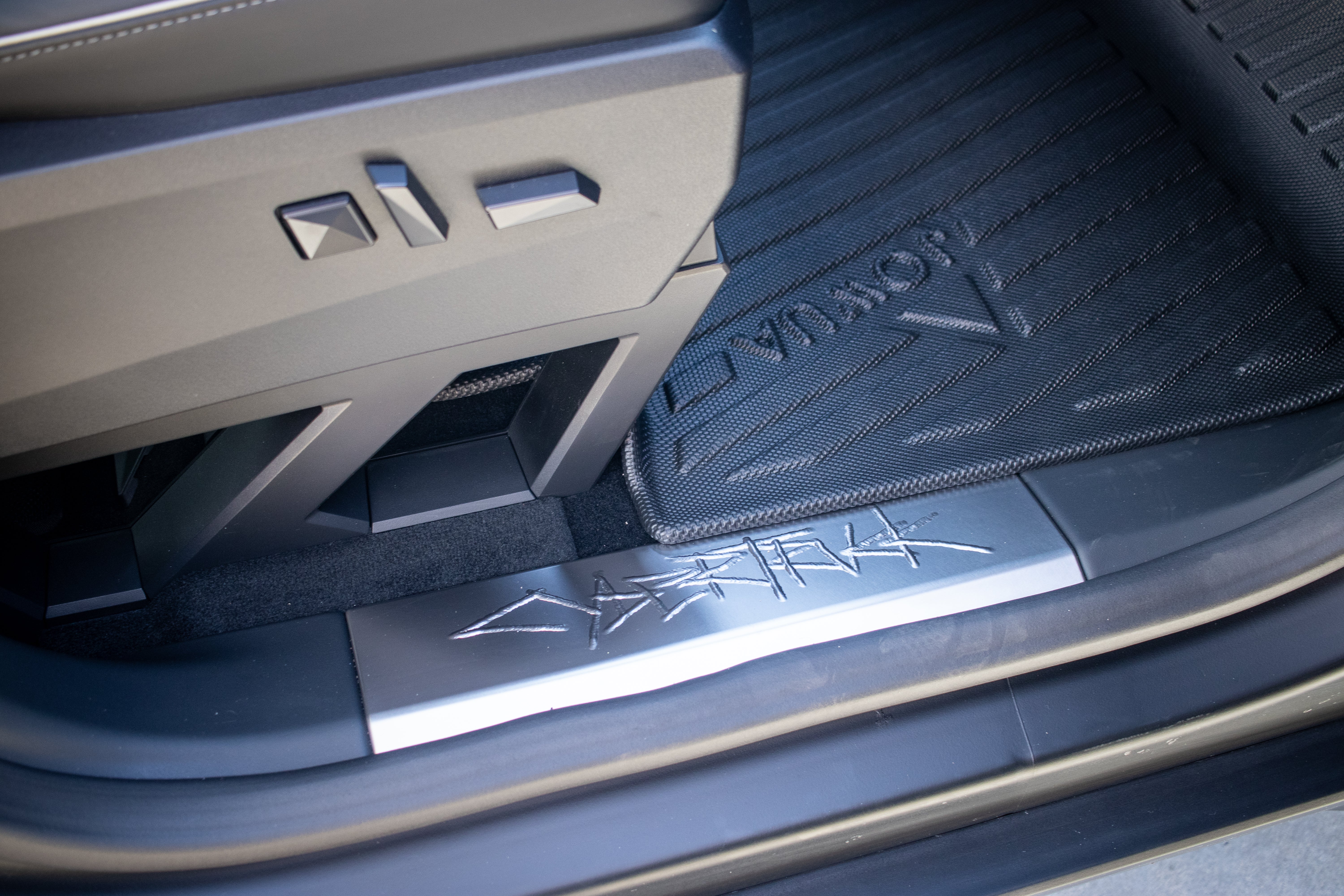 A close-up of JOWUA's All Weather Floor Liners for the Tesla Cybertruck showcases metallic accents and geometric shapes, including the word 