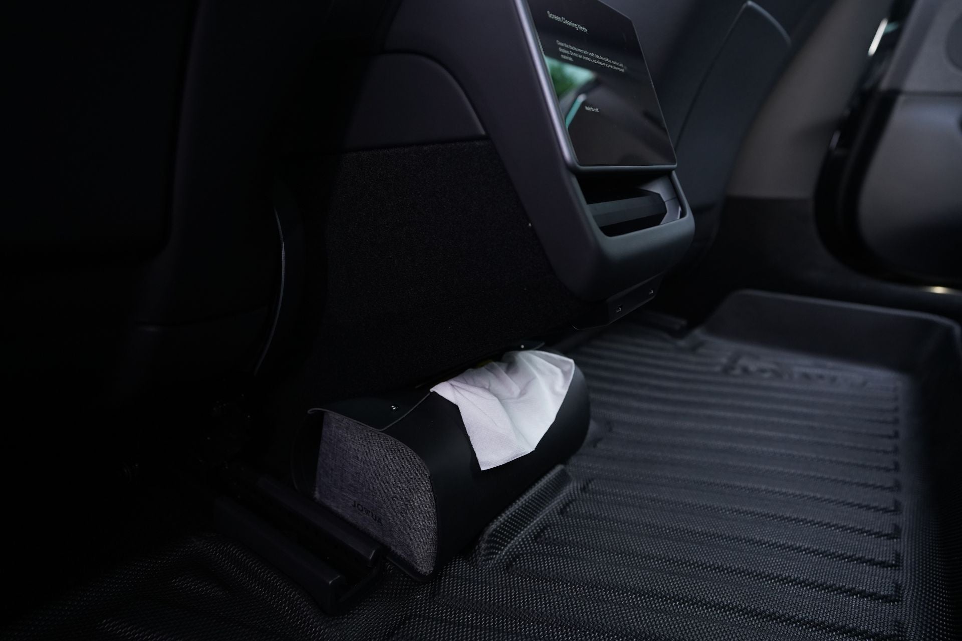 The image showcases the back seat of a Tesla Model 3, featuring JOWUA's Model 3 All-Weather Floor Liners (Right Hand Drive Version). Elegantly placed on the floor mat is a MagSafe Tissue Box Cover, highlighting its textured fabric with neatly arranged tissues for easy access.