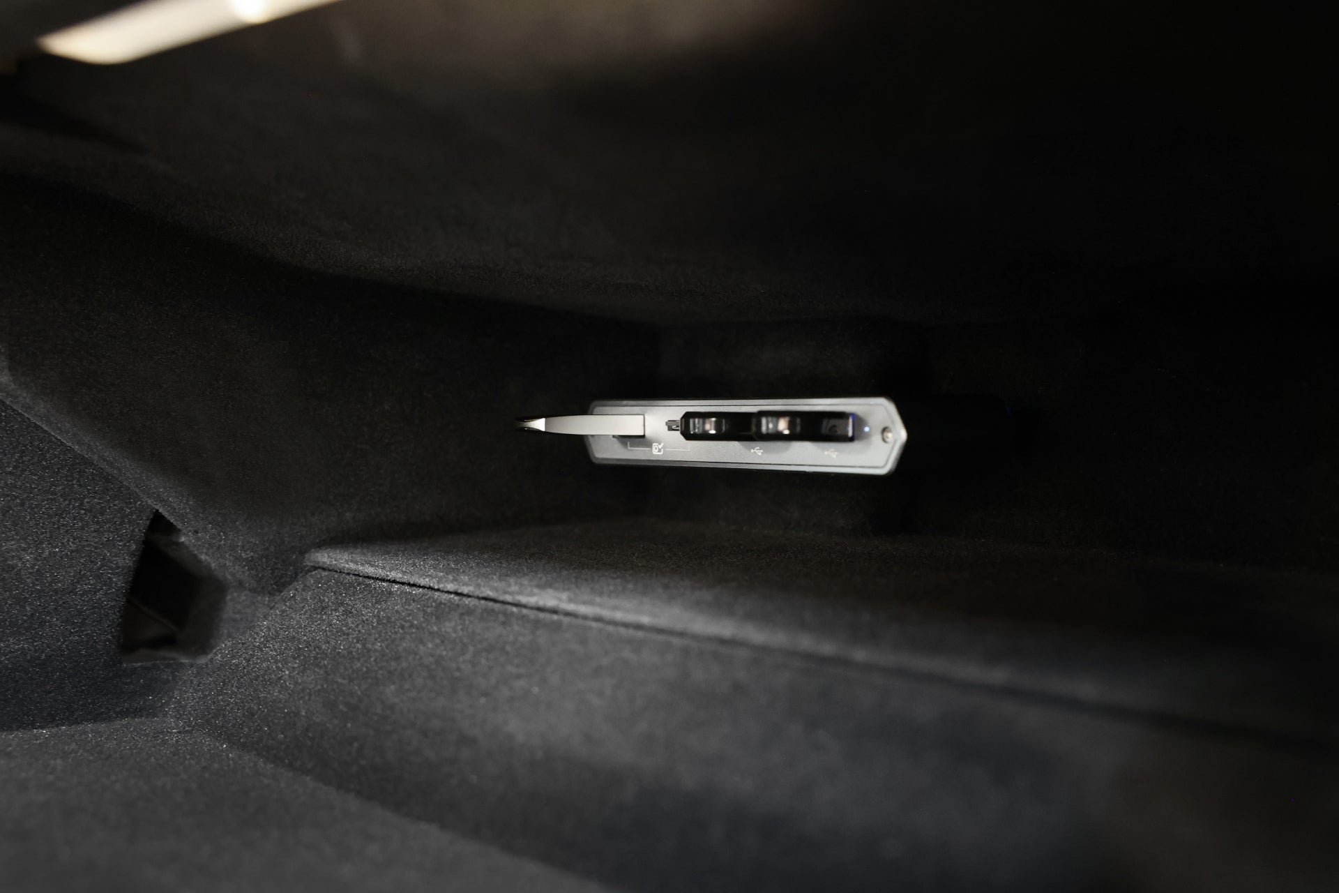 A close-up of a car glove compartment interior highlights a JOWUA accessory, the Dual-Function Storage HUB (MicroSD Reader & Tesla USB), set against a dark background.