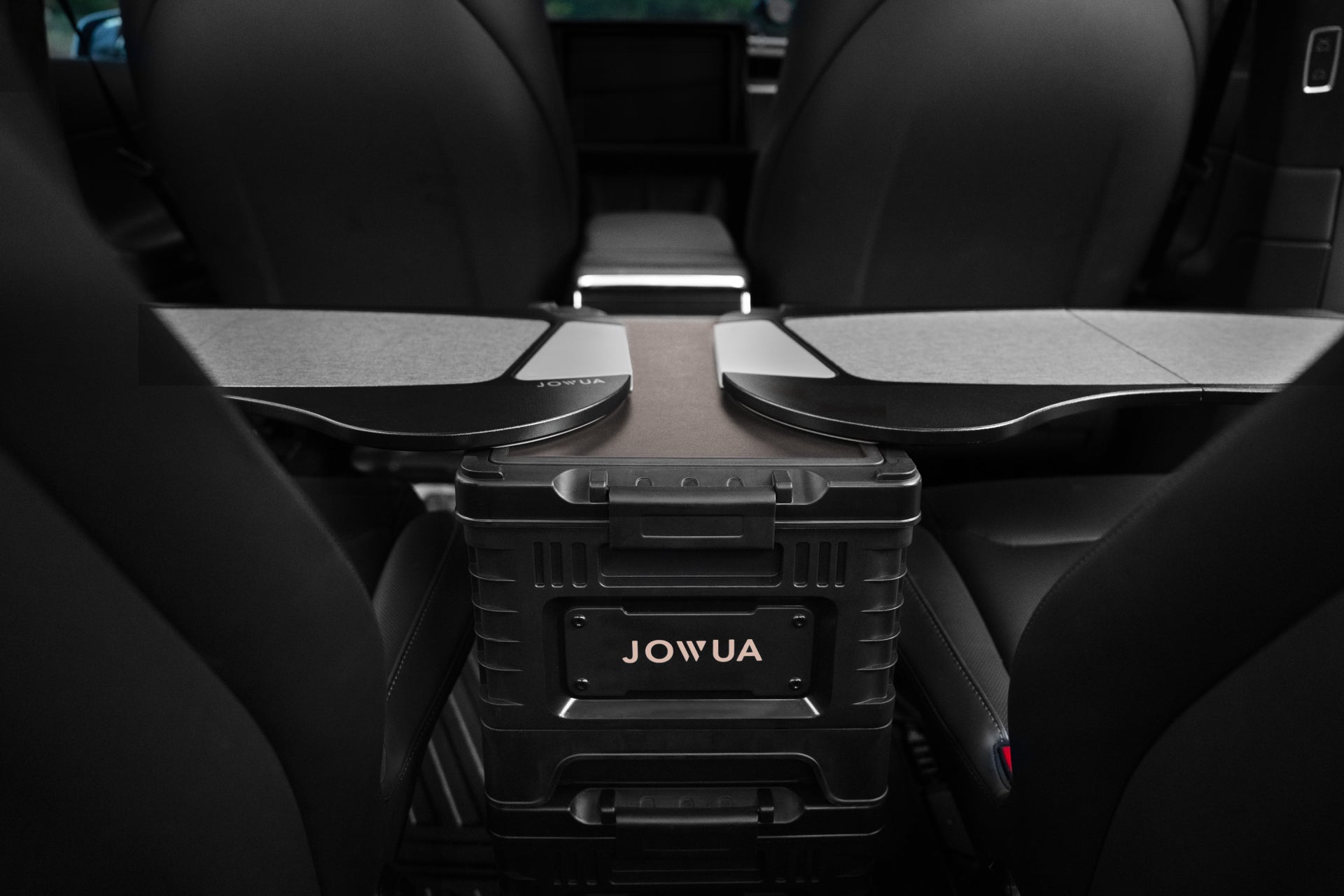 The interior of the car highlights a sleek JOWUA 30L Stackable Storage Box and Trunk Organizer designed for Teslas, strategically placed between the rear seats. This organizer features foldable trays on top. The seats are upholstered in black leather, complementing the dashboard to enhance the elegant ambience.