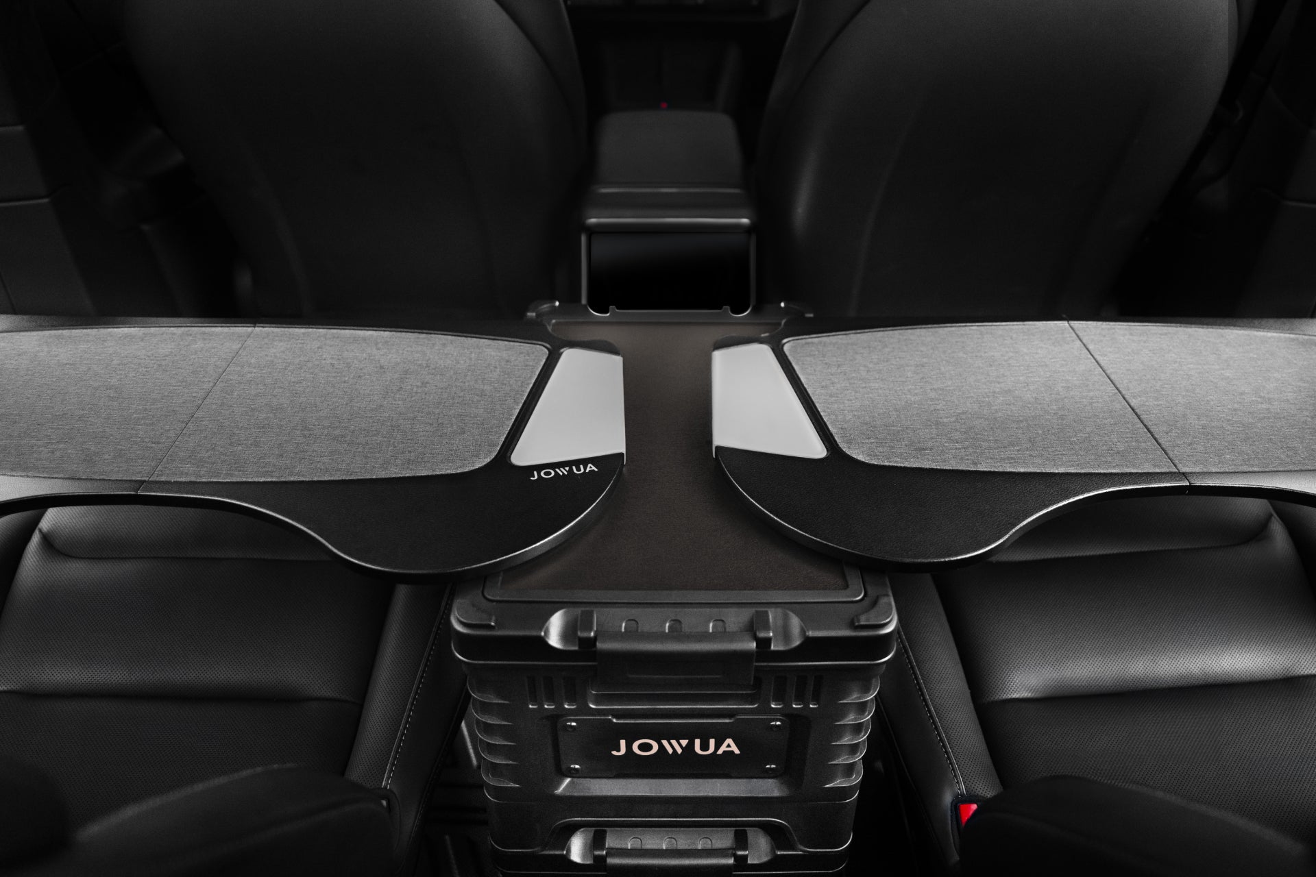 A car interior with black leather seats and a central console features foldable trays from JOWUA, perfect for crafting a temporary work or dining area. Elevate your travel experience by adding the 30L Stackable Storage Box and Trunk Organizer for Teslas, ensuring an orderly ride with extra rear seat storage.