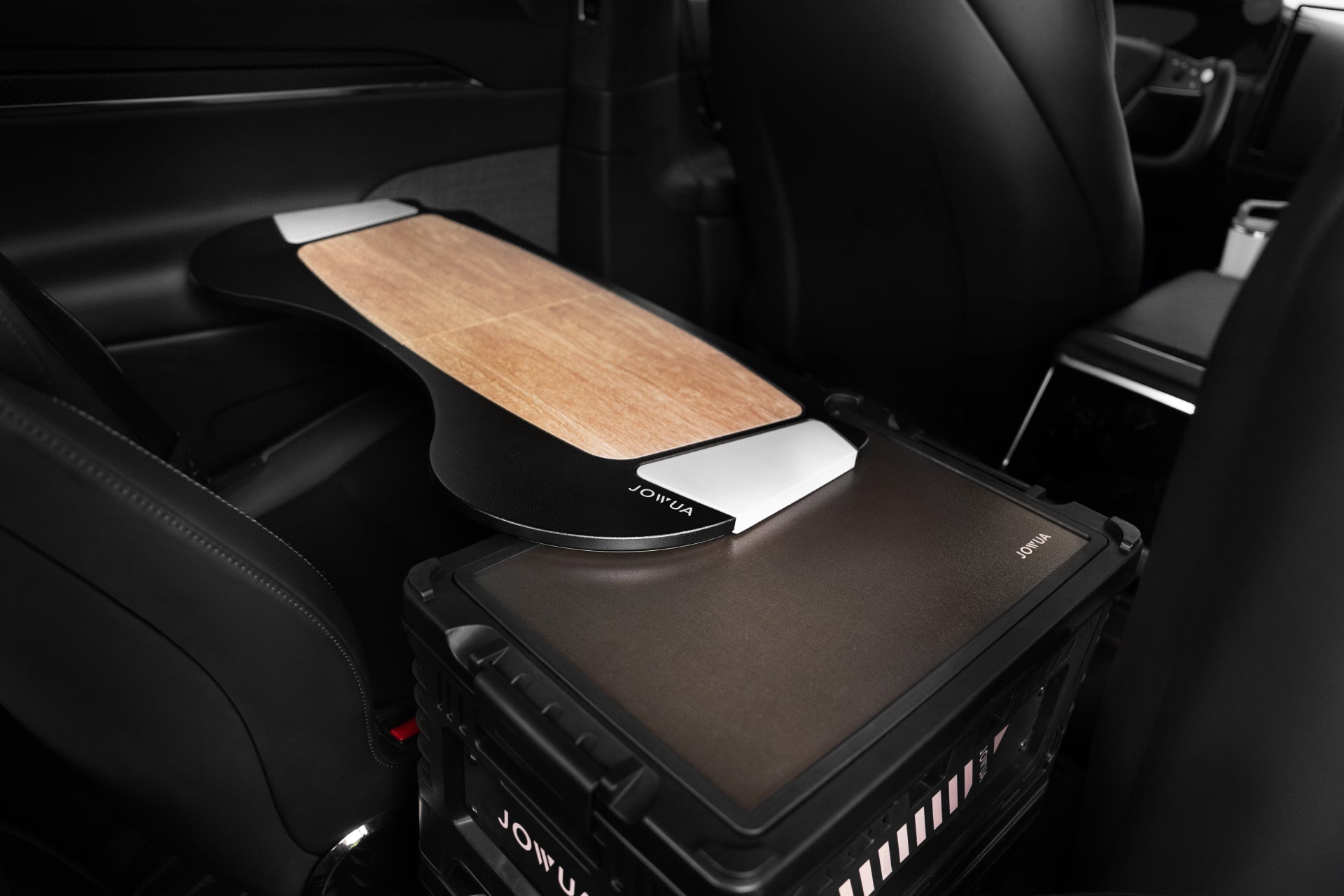 A car interior showcasing a 30L Stackable Storage Box and Trunk Organizer for Teslas from JOWUA, complemented by a custom wooden board on the back seats, with a sleek black box labeled 