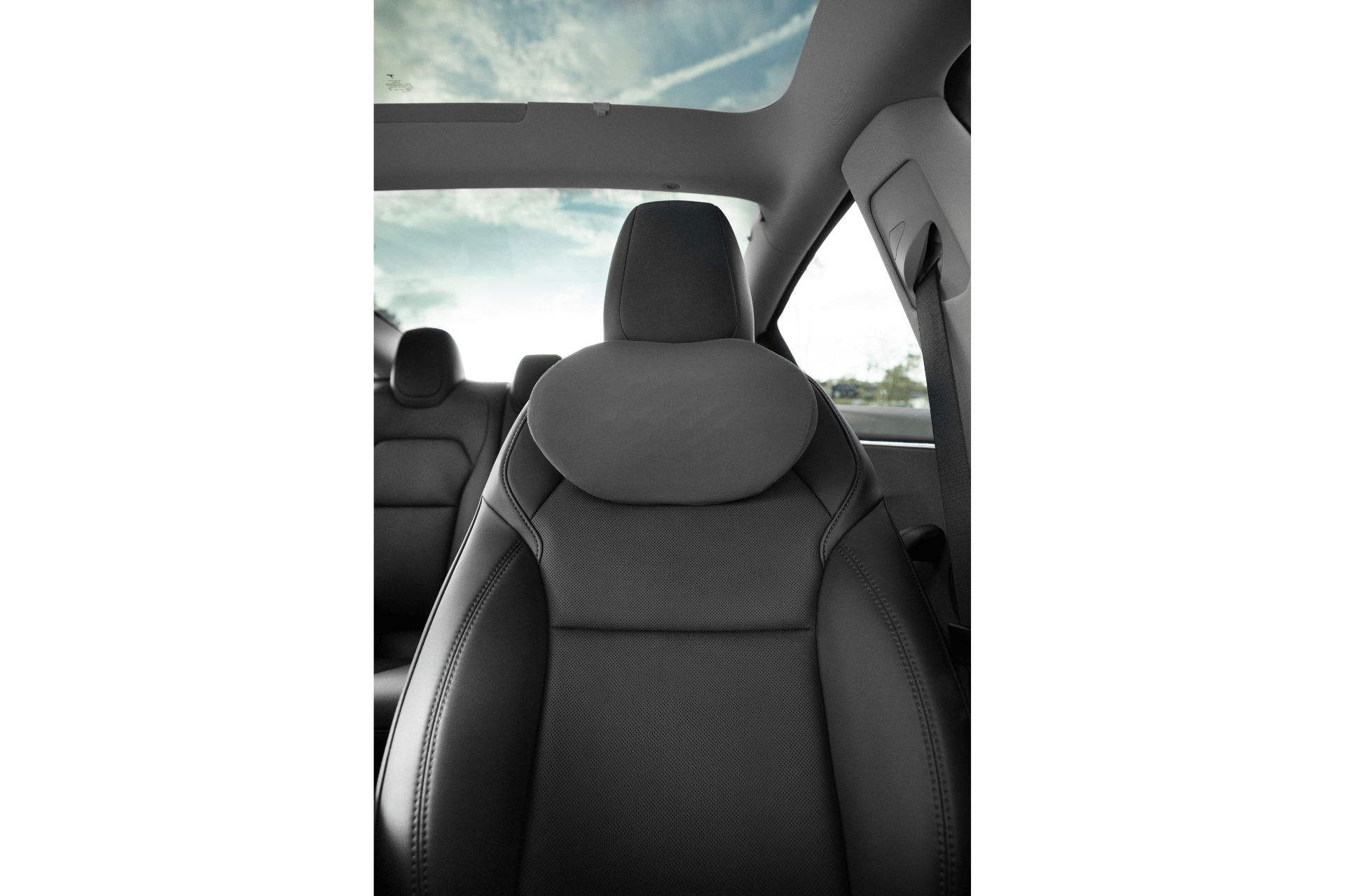 Close-up of a car interior featuring JOWUA brand black leather seats with dual-material accents and a panoramic sunroof, showcasing the blue sky and clouds.