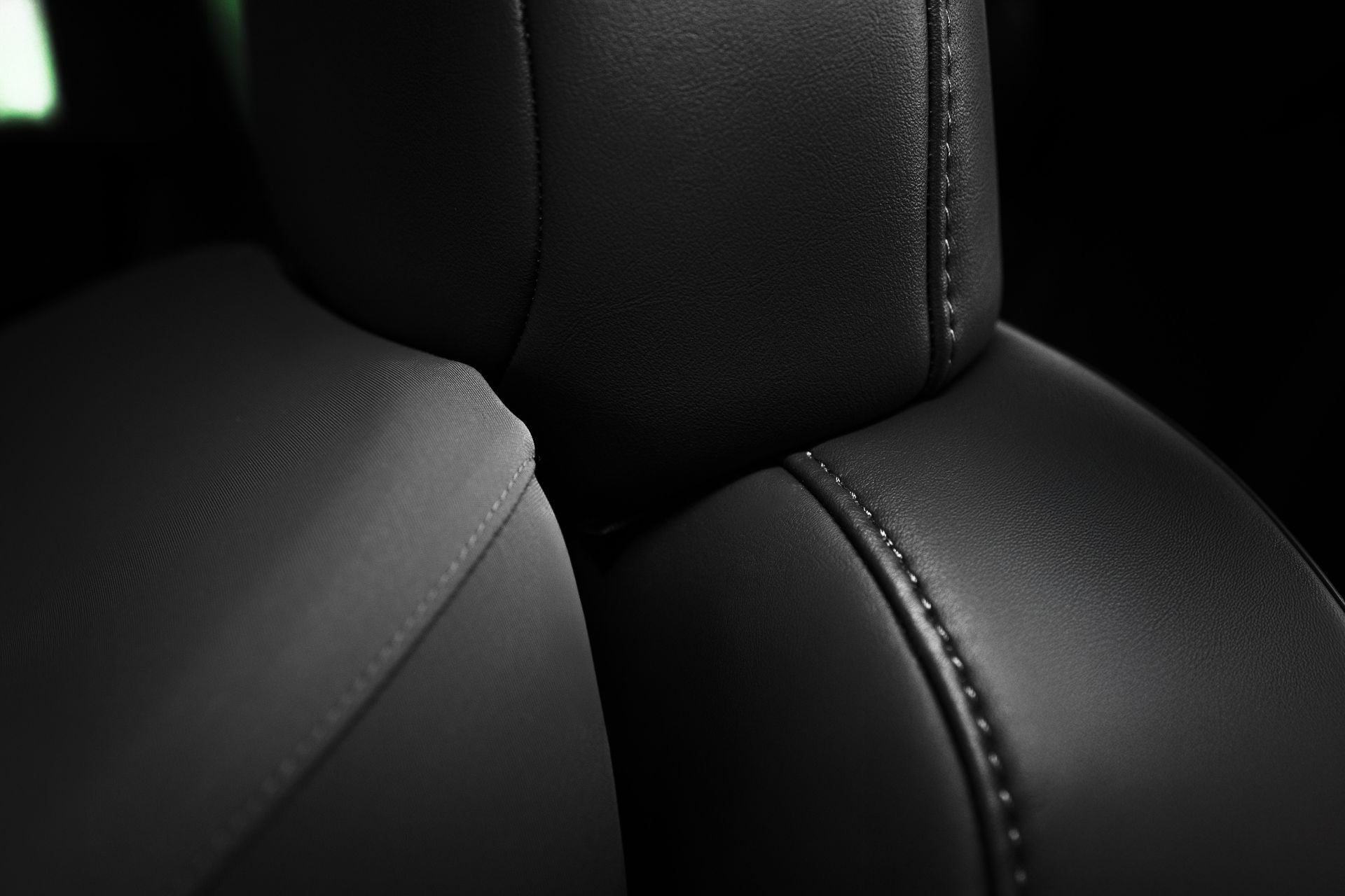 Close-up of the JOWUA Car Neck Pillow with black leather and precise stitching. The smooth texture, detailed seam, and lighting highlight its contours and craftsmanship, showcasing its ergonomic design.