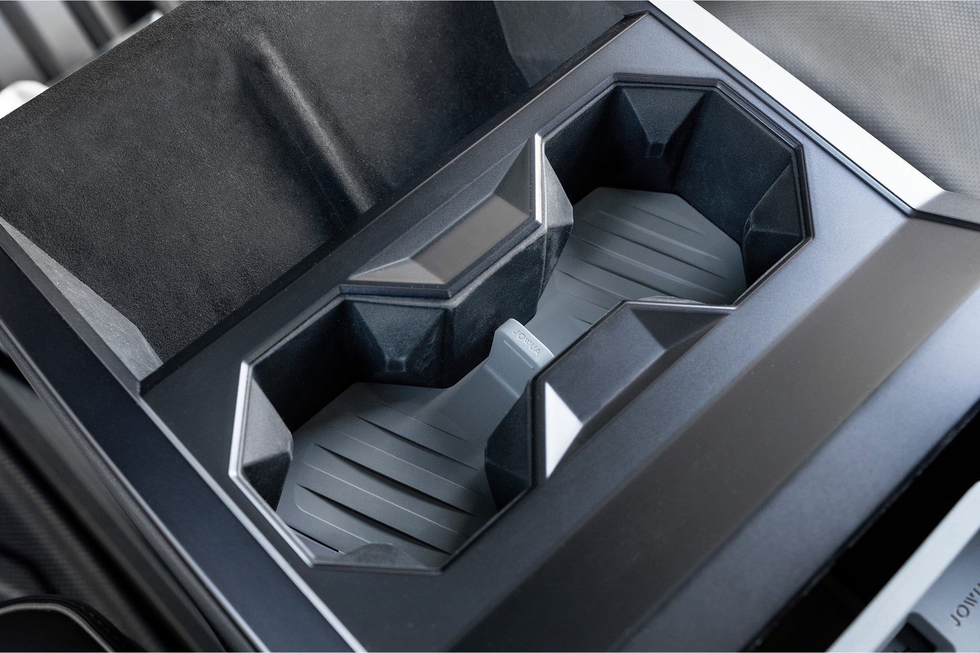 Close-up of JOWUA's Center Console Set for Tesla Cybertruck, showcasing a futuristic cup holder with angular shapes and textured surfaces in a sleek, modern finish. Premium silicone accents enhance the avant-garde aesthetic.