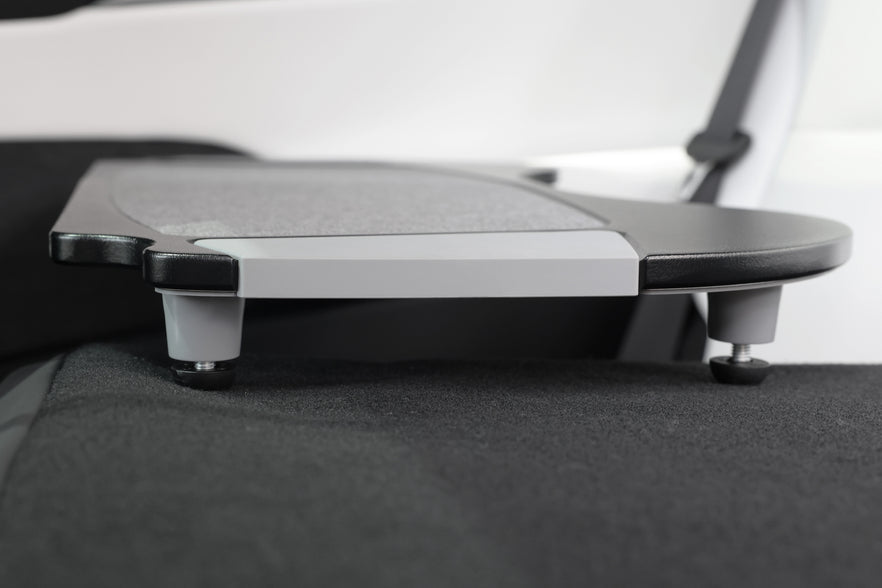 Close-up of the JOWUA Foldable Car Tray for Tesla, integrated into the back of a car seat. It features a sleek design with premium PU leather and two sturdy support legs. Ideal as an accessory for Tesla Model S/3/X/Y, the background highlights the car's elegant interior upholstery.