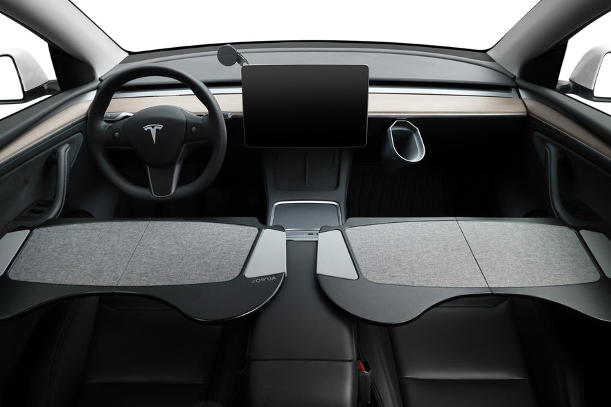 Interior view of a car showcasing premium materials, such as a sleek, minimalist dashboard with an expansive touchscreen display above the console. The steering wheel is visible, and sunshades are extended across the dashboard. A JOWUA Foldable Car Tray for Tesla perfectly complements the light gray and black color scheme.