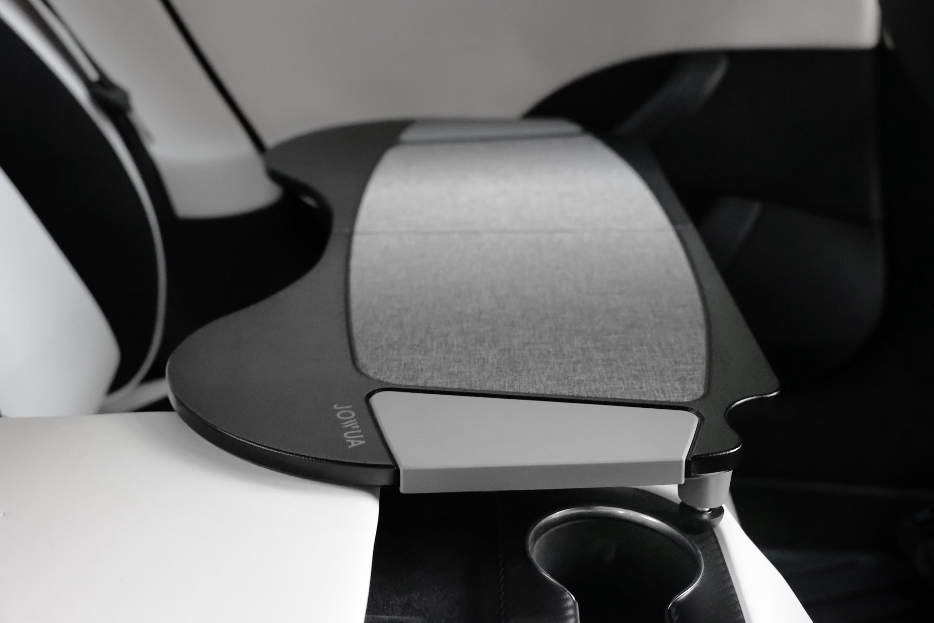 The interior of the Tesla Model S includes a foldable car tray from JOWUA, crafted from premium PU leather with a gray textured surface. Positioned beside a white seat and above a cup holder, it beautifully combines functionality with sleek design that aligns seamlessly with Tesla's innovative spirit.