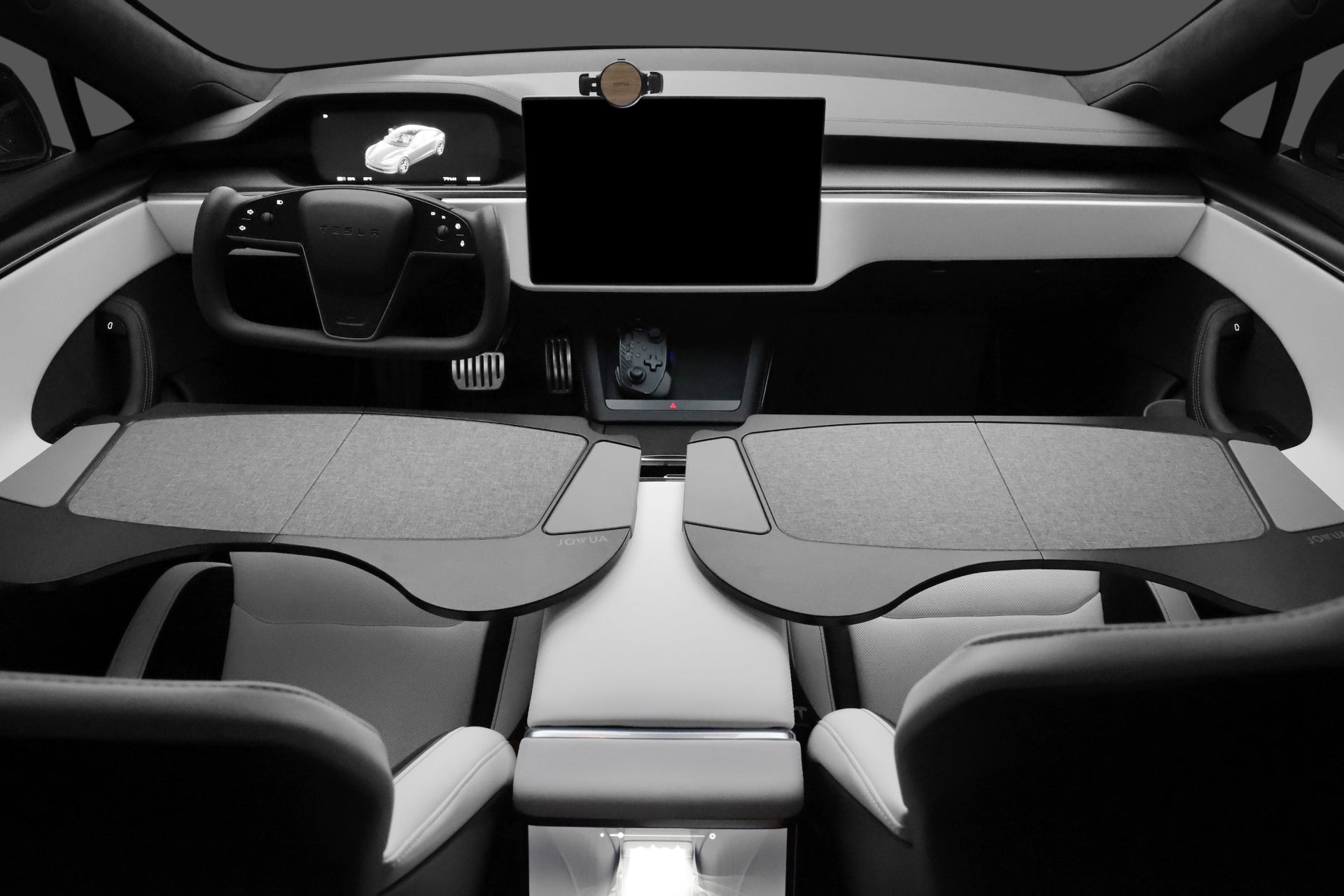 Interior of a modern electric car showcasing a futuristic dashboard, a large central touchscreen, and streamlined controls. The seats are enhanced with the JOWUA Foldable Car Tray for Tesla, crafted from premium materials. The overall design is sleek with a black, white, and gray color scheme, making it an ideal match for Tesla Model S/3/X/Y accessories.