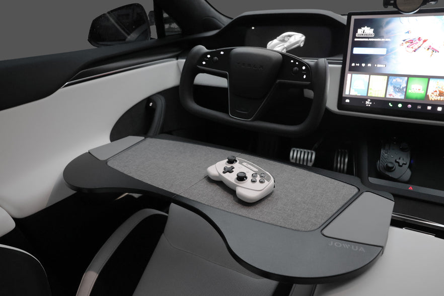 The interior of this car includes a stylish steering wheel and a sizable touchscreen display on the dashboard. The JOWUA Foldable Car Tray for Tesla, complete with a game controller, highlights Tesla Model S/3/X/Y accessories for an unparalleled in-car entertainment experience with premium materials.