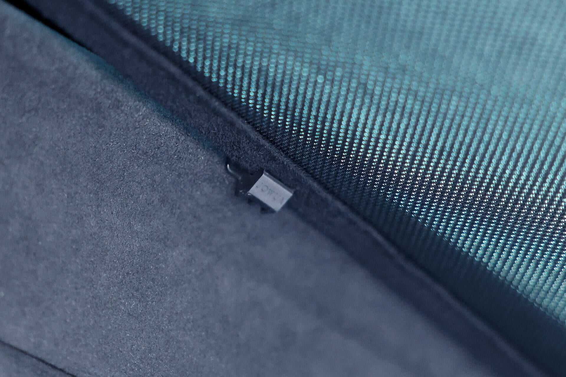 A close-up of a small black sensor embedded in a dark surface highlights the JOWUA Glass Roof Sunshade-Separate Design (Model X). The backdrop, featuring teal fabric, suggests an innovative sunroof design that blends functionality with elegance.