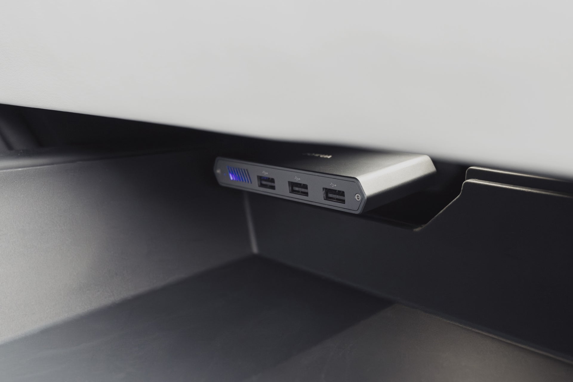 A close-up of a JOWUA Dual-Function Storage HUB, featuring a MicroSD reader and Tesla USB, with four ports for seamless data expansion, mounted beneath a white surface.