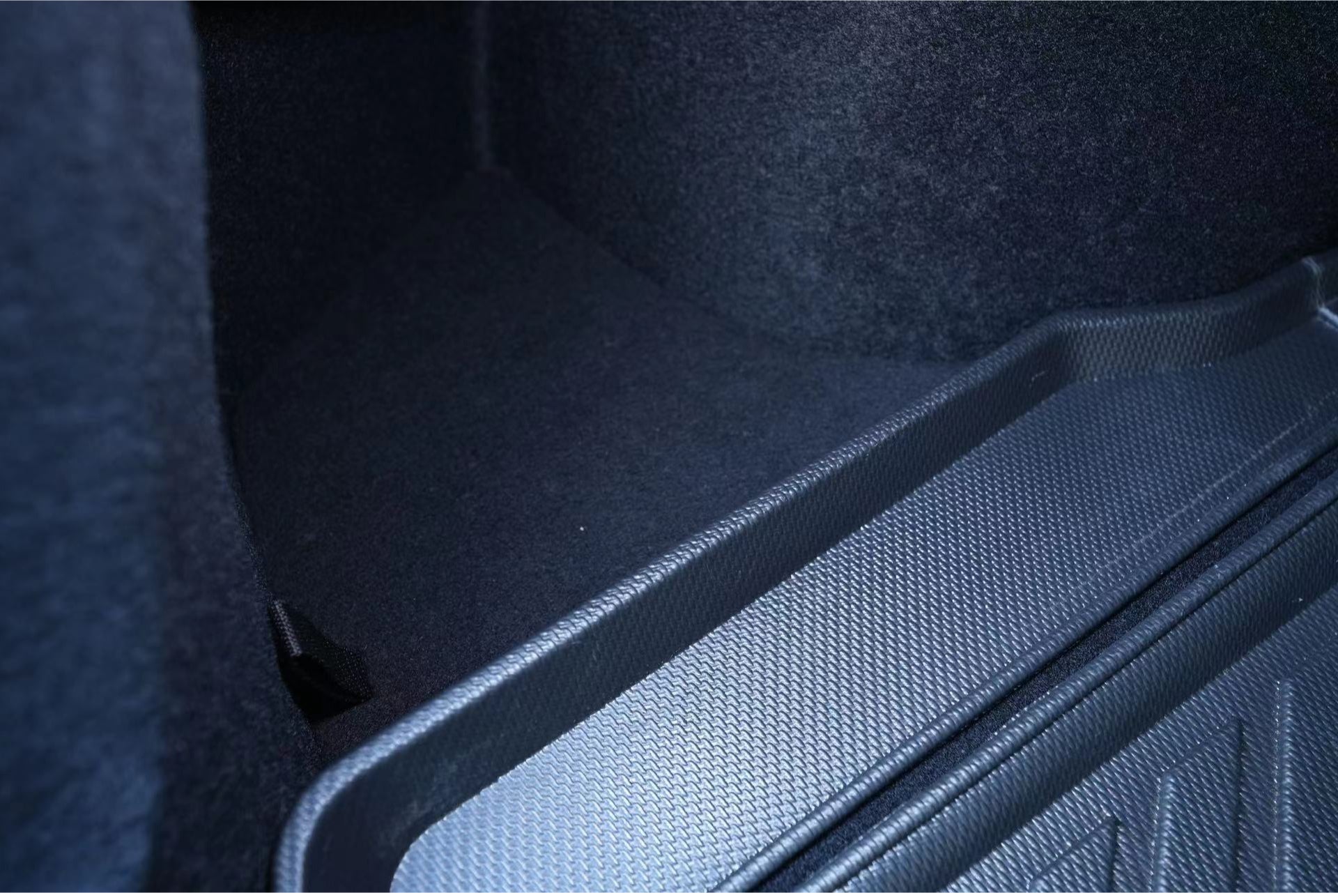 Close-up image of the dark car trunk interior with textured surfaces, showcasing the raised rubber mat on the right side made from waterproof TPE material, ideal for JOWUA Model 3 All Weather Trunk Combo (Reengineered Model 3 Highland, 2024+).