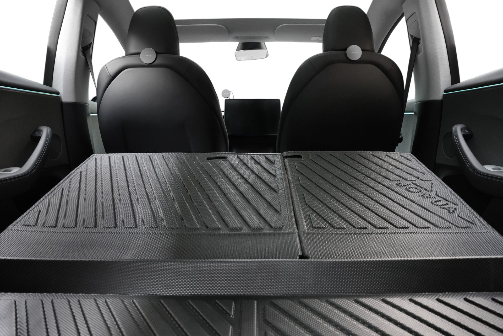 A view of the car interior from the open trunk shows the rear seats folded down to create a flat cargo space. The dashboard and front seats display a minimalist and modern design, enhanced by JOWUA's Trunk Combo, featuring durable all-weather trunk liners made from TPE material for added protection. This product is part of their reengineered Model 3 Highland collection for 2024 and beyond.