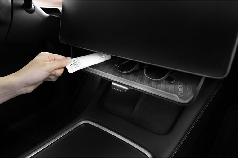 A person’s hand discreetly places a small item, possibly a tube or pen, inside the glove compartment of a JOWUA Under Screen Invisible Station. The compartment also contains sunglasses, highlighting its seamless and hidden integration.