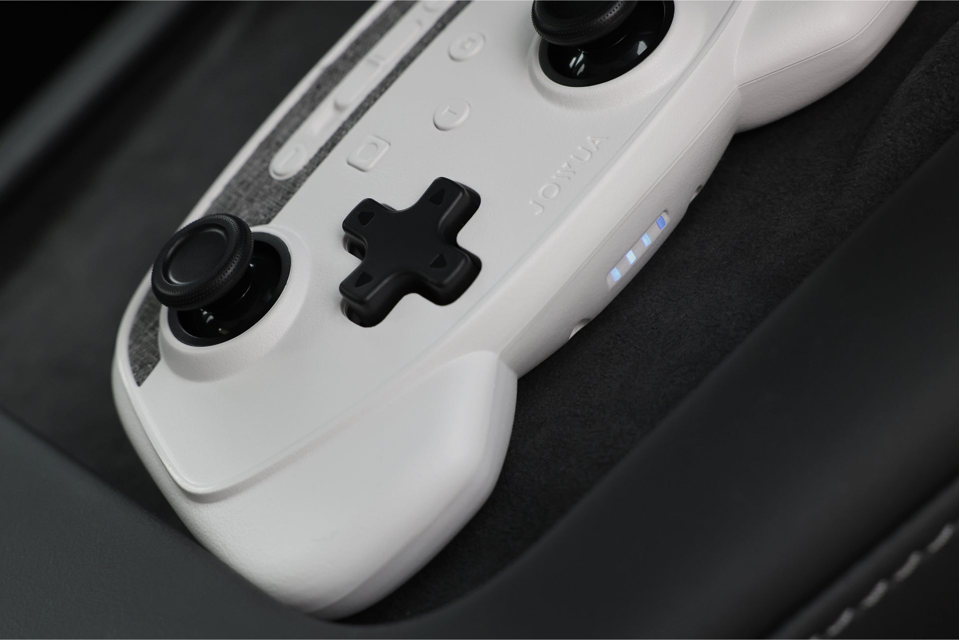 A close-up of a JOWUA Wireless Tesla Game Controller from the Model S/3/3HL/X/Y/Cyber Combo showcases its sleek white design with black buttons, including dual analog sticks and a cross-shaped D-pad. It features Bluetooth Connect capabilities along with two LED indicators on the front, elegantly resting on a dark surface.