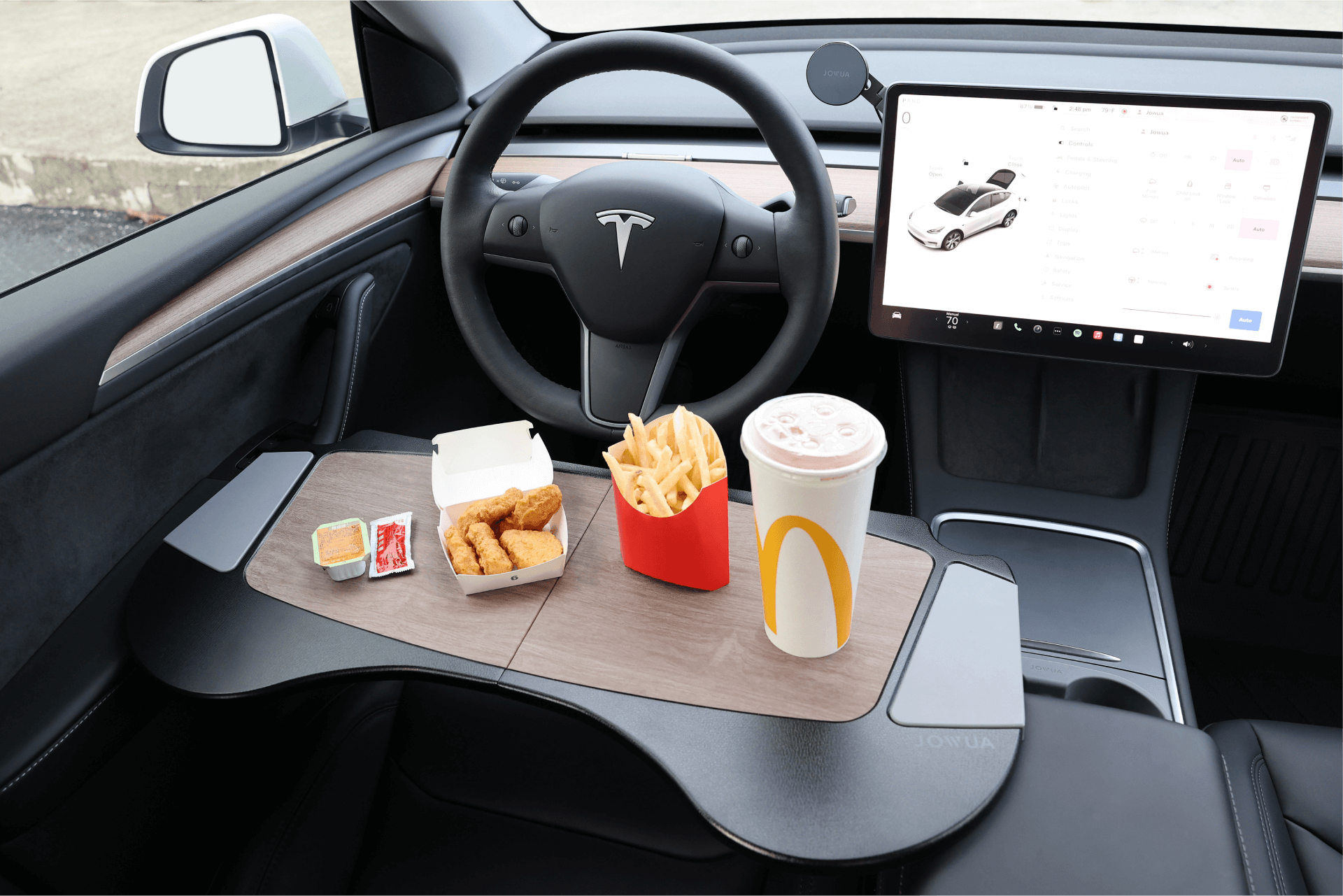 A JOWUA Foldable Car Tray for Tesla, designed to attach to the steering wheel, is perfect for displaying McDonald's food such as chicken nuggets with sauce, fries in their iconic red container, and a large drink cup. Made from premium materials, this innovative accessory seamlessly enhances the sleek design of your Tesla Model S/3/X/Y.