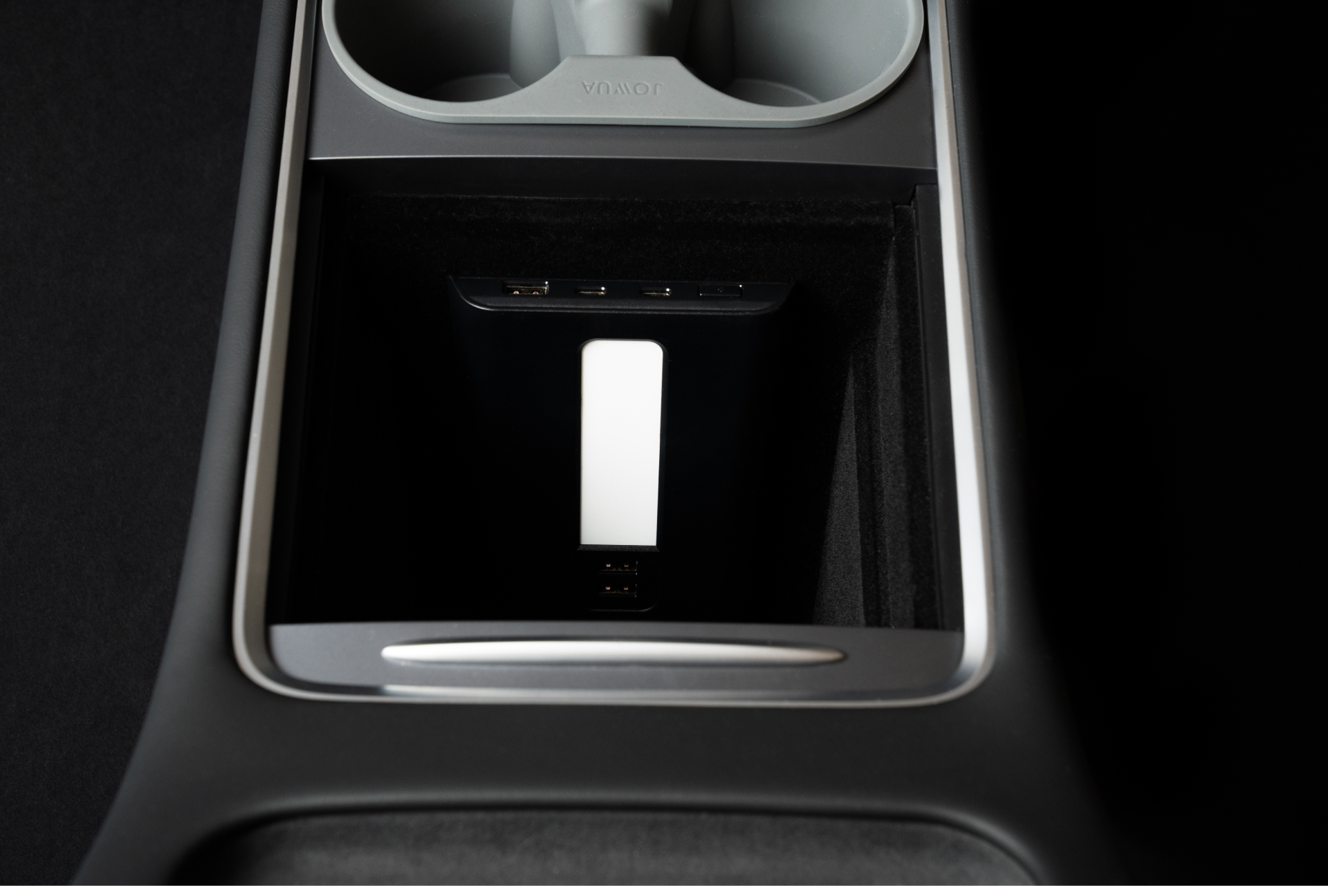 The image showcases the interior of a Tesla Model 3, highlighting a sleek black center console design. It features a JOWUA USB Hub for Tesla Model 3/Y with Dual USB-C 45W and LED warm light, ensuring seamless device connectivity.