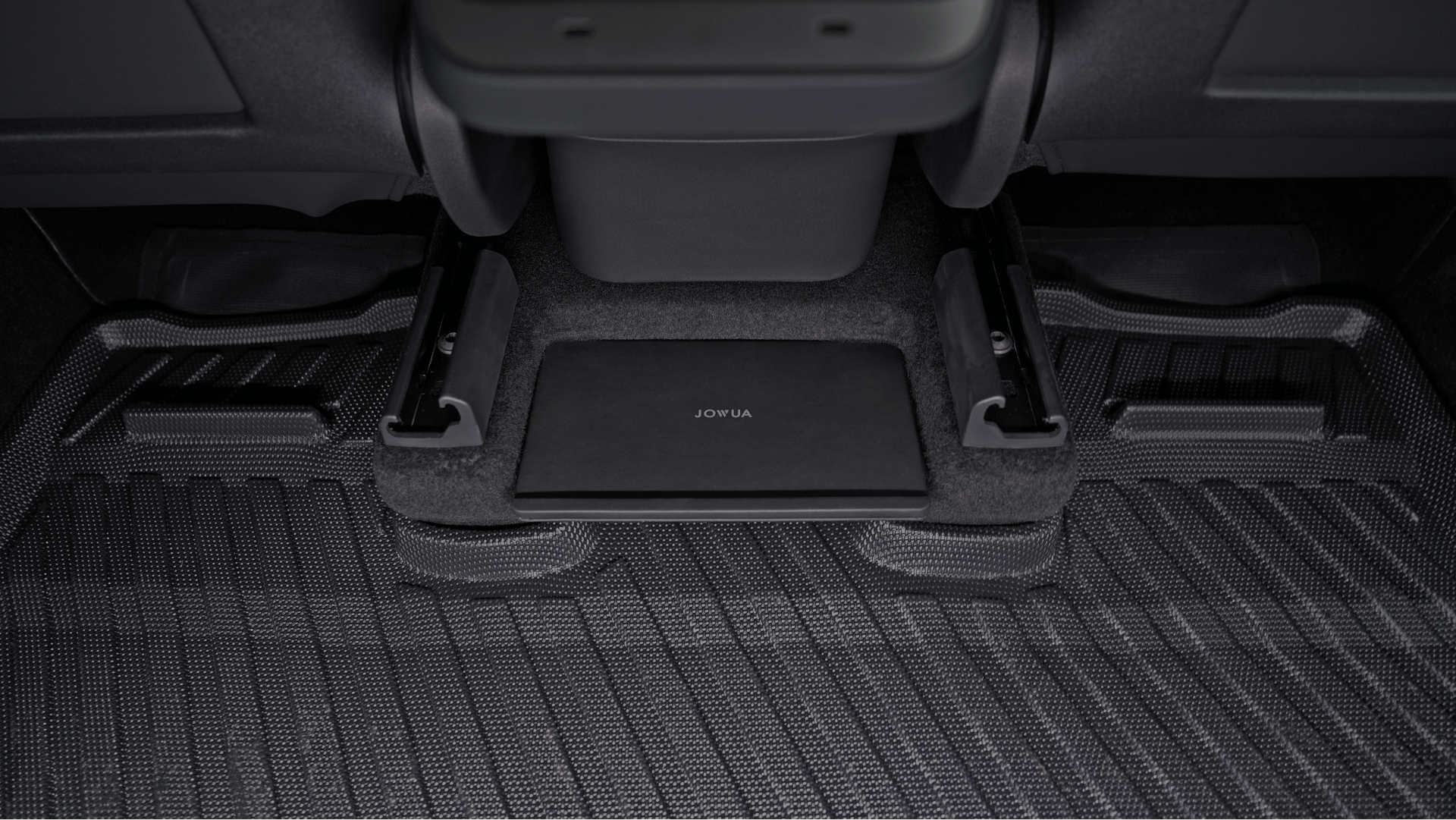 A black Model Y Tissue Box Holder Set by JOWUA, designed specifically for a Tesla Model Y, fits snugly under the vehicle's seat. The textured dark carpet complements its sleek design. With ample space and an integrated tissue holder, it blends seamlessly into the car's interior while enhancing storage solutions.